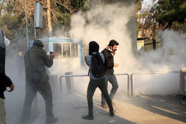 Iranian students run for cover from tear gas at the University of Tehran during a demonstration driven by anger over economic problems, in the capital Tehran on December 30, 2017. Students protested in a third day of demonstrations, videos on social media showed, but were outnumbered by counter-demonstrators.  STR / AFP