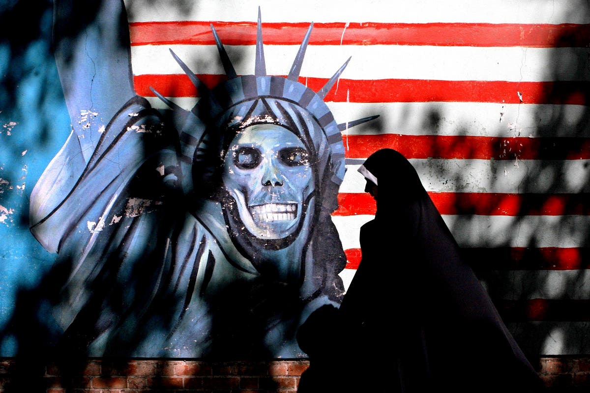 An Iranian woman walks past graffiti art characterizing the US Statue of Liberty. (AP)