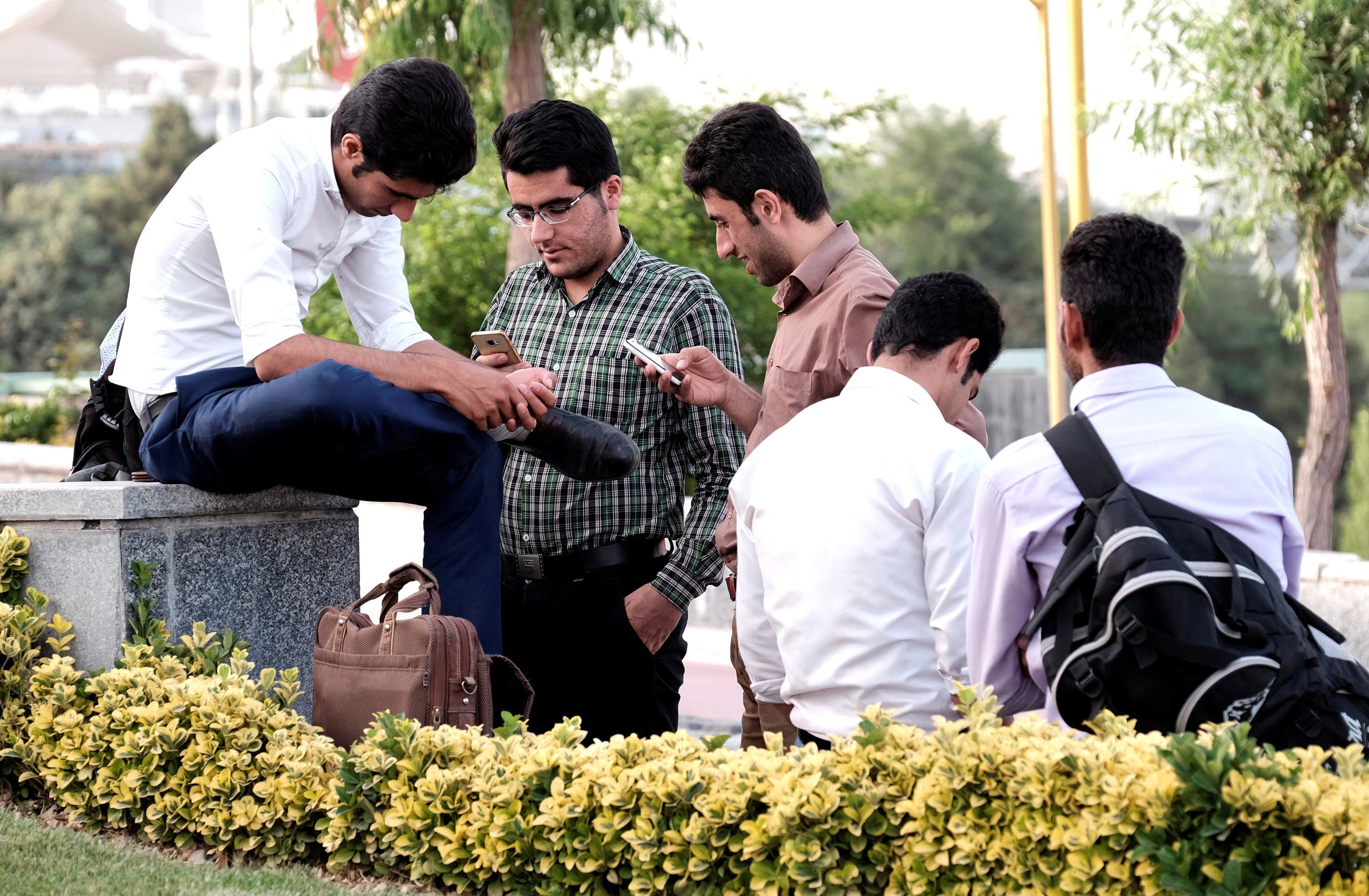 Iranian youth use their mobile phones as they rest at a park in Tehran on May 16, 2017. (Reuters)