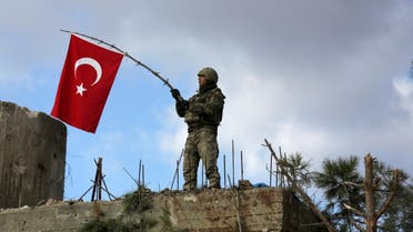 A Turkish soldier waves a flag on Mount Barsaya, northeast of Afrin. (Reuters)