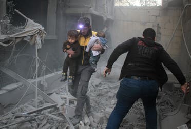 A Syrian man carries two children in the rubble of buildings following regime air strikes on the rebel-held besieged town of Douma in the eastern Ghouta region on February 7, 2018. (AFP)