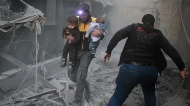 A Syrian man carries two children in the rubble of buildings following regime air strikes on the rebel-held besieged town of Douma in the eastern Ghouta region on February 7, 2018. (AFP)