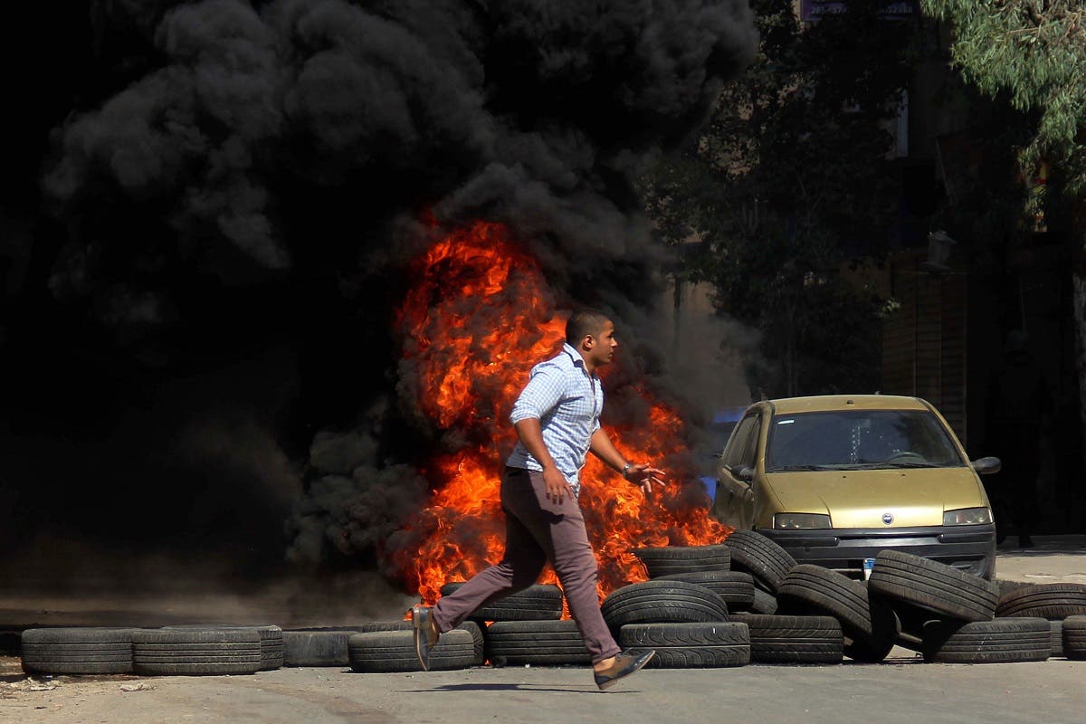 A man runs past burning tires set on fire during clashes between the security forces and supporters of the Muslim Brotherhood outside Al-Azhar University in Cairo, Egypt, Friday, May 23, 2014. (AP)