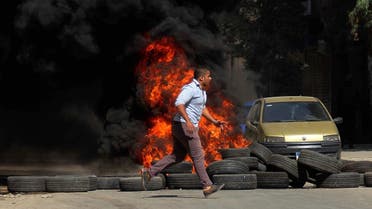 A man runs past burning tires set on fire during clashes between the security forces and supporters of the Muslim Brotherhood outside Al-Azhar University in Cairo, Egypt, Friday, May 23, 2014. (AP)