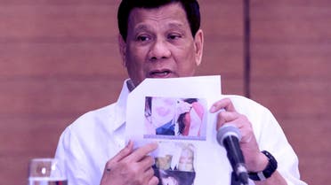 Philippine President Rodrigo Duterte shows a photo of a Filipina worker in Kuwait, of whom he said she had been "roasted like a pig". (AFP)