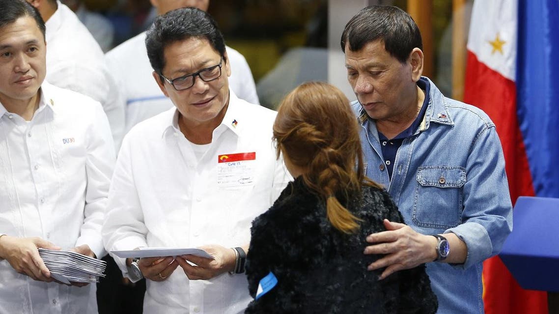 Philippine President Rodrigo Duterte hands cash gifts to Filipino Overseas Workers who were repatriated from Kuwait. (AP)