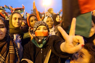 A Libyan woman flashes the victory gesture while others wave national flags as they attend a celebration marking the seventh anniversary of the Libyan revolution. (AFP)