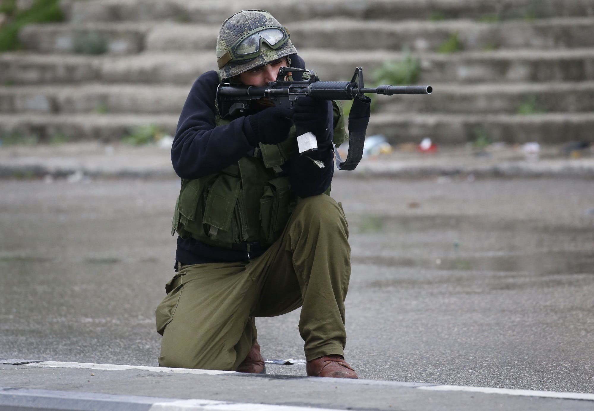 An Israeli soldier aims his gun during clashes with Palestinian protestors in Hebron, on February 17, 2018. (AFP)