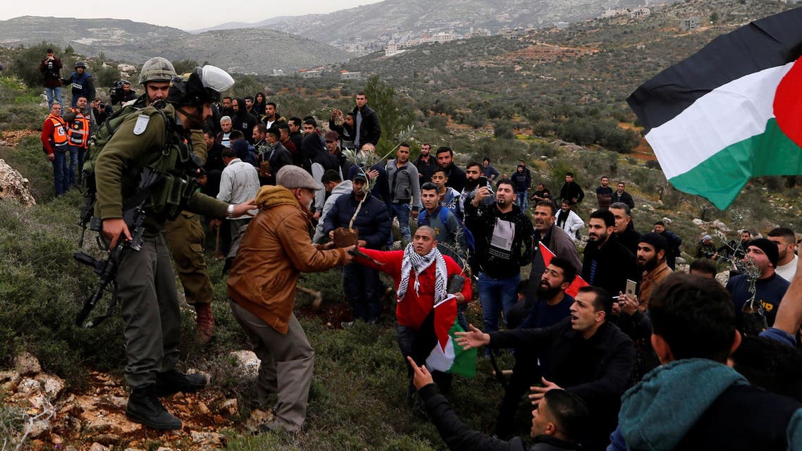 Palestinians try to plant olive trees as Israeli troops stand guard during a protest near Nablus on February 15, 2018. (Reuters)