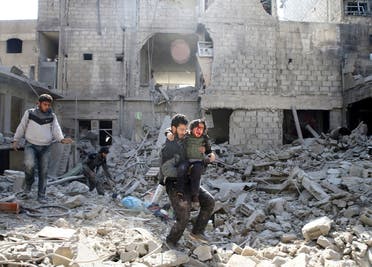 A man carries an injured boy as he walks on rubble of damaged buildings in the rebel held besieged town of Hamouriyeh. (Reuters)
