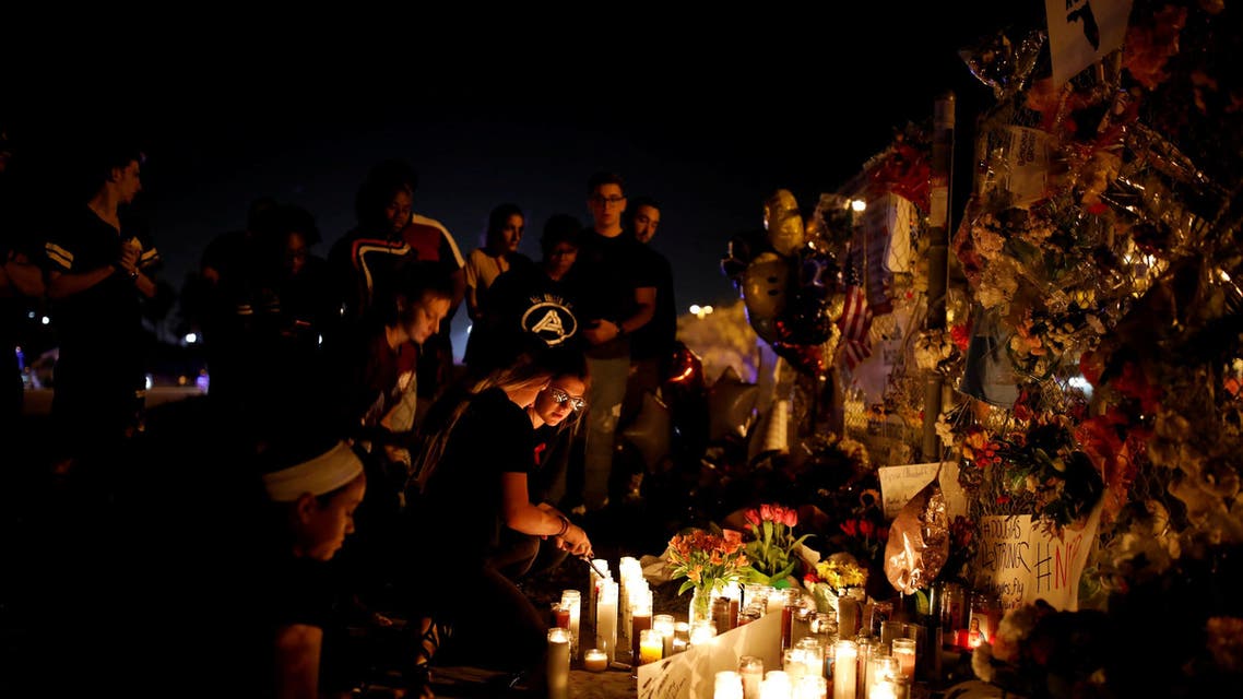 People light candles in front of mementoes placed in front of the fence of the Marjory Stoneman Douglas High School to commemorate the victims of the mass shooting, in Parkland, Florida, U.S., February 21, 2018. REUTERS/Carlos Garcia Rawlins TPX IMAGES OF THE DAY