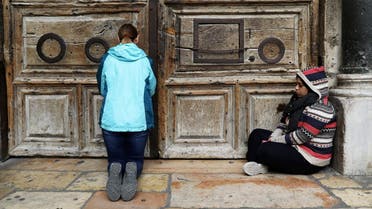 Worshipper sit next to the closed doors of the Church of the Holy Sepulchre in Jerusalem's Old City. (Reuters)