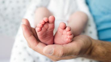 Unrecognizable father with newborn baby son, legs and hand - Stock image... 