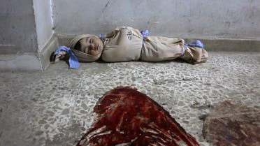 The body of a Syrian baby lies wrapped in a shroud on the floor of a makeshift clinic following Syrian government bombardments in Douma, in the besieged Eastern Ghouta region on the outskirts of the capital Damascus on February 22, 2018. (AFP)