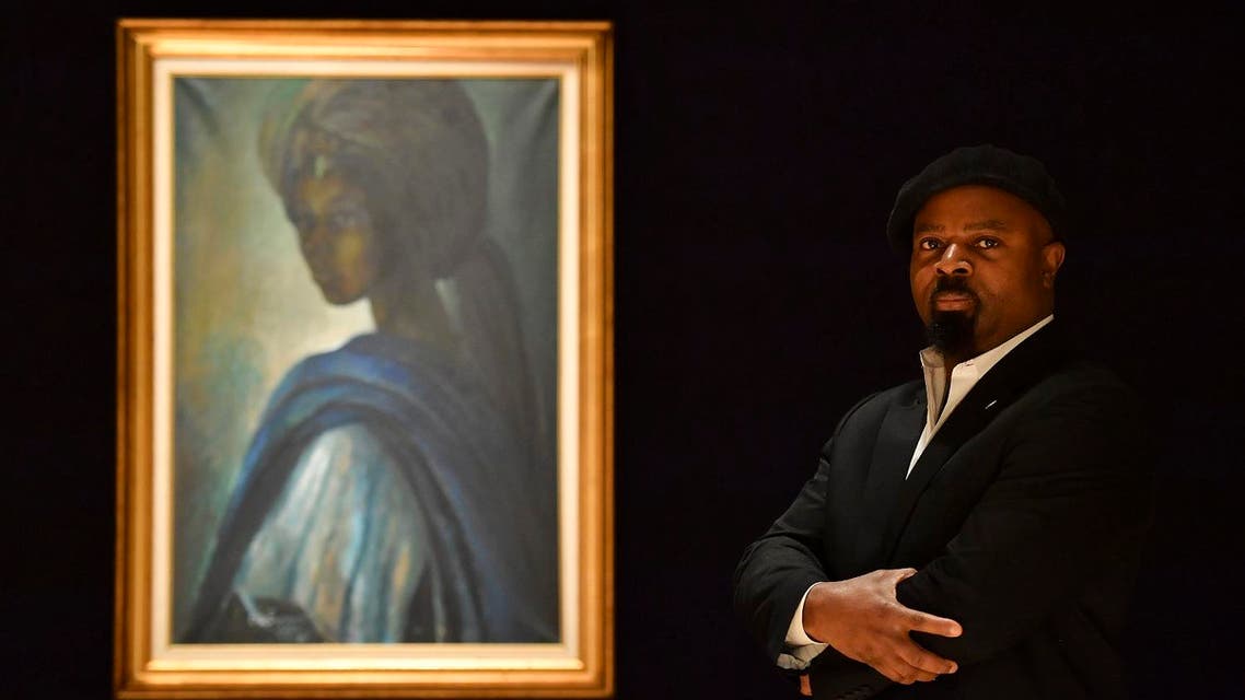 Nigerian author Ben Okri poses with a work of art by Nigerian painter and sculptor Ben Enwonwu entitled ‘Tutu’ at auction in Bonhams auction house London on February 7, (AFP)