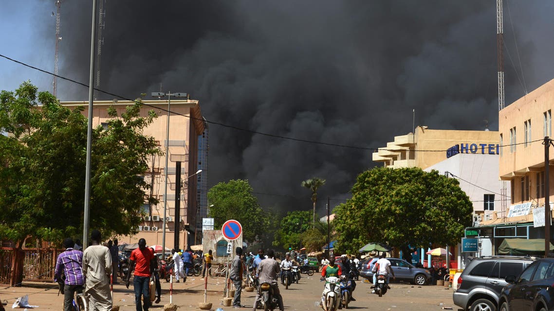 People watch as black smoke rises as the capital of Burkina Faso came under multiple attacks on March 2, 2018, targeting the French embassy, the French cultural centre and the country's military headquarters. Witnesses said five armed men got out of a car and opened fire on passersby before heading towards the embassy, in the centre of the city. Other witnesses said there was an explosion near the headquarters of the Burkinabe armed forces and the French cultural centre, which are located about a kilometre (half a mile) from the site of the first attack.  Ahmed OUOBA / AFP