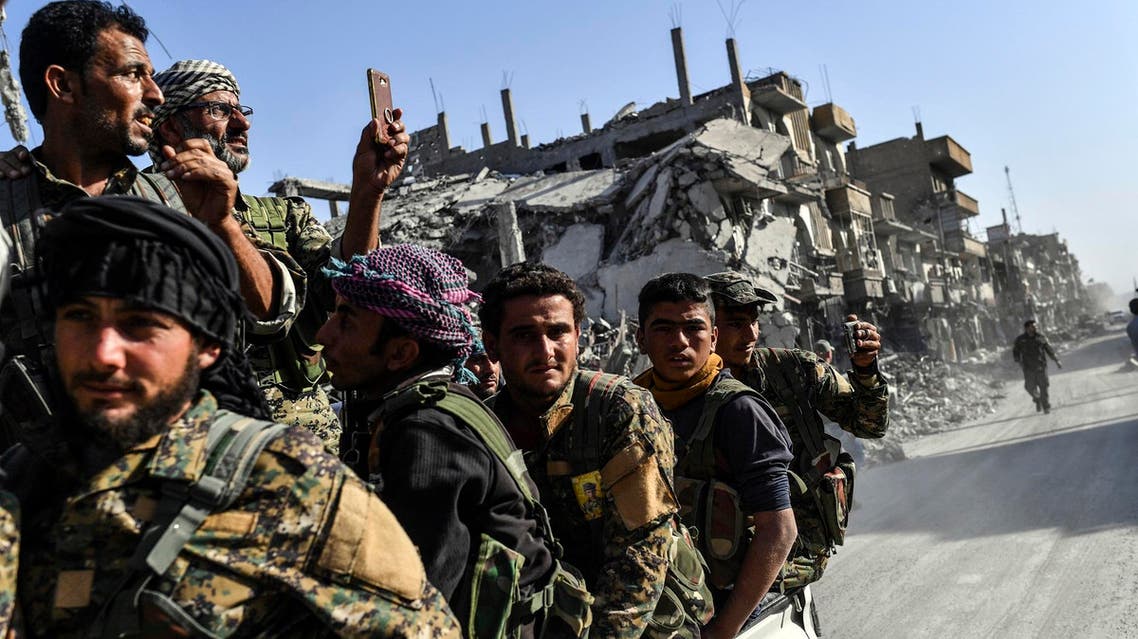 Kurdish fighters of SDF ride in a truck passing damaged buildings in Raqqa on October 20, 2017. (AFP)