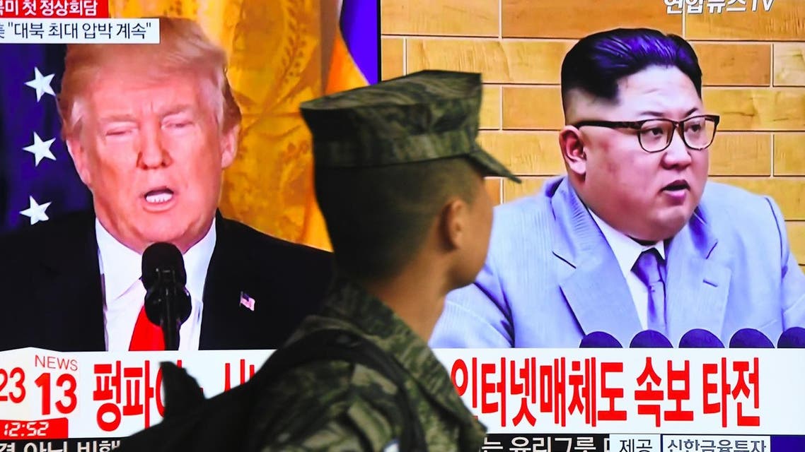 A South Korean soldier walks past a TV screen showing pictures of US President Donald Trump (L) and North Korean leader Kim Jong Un at a railway station in Seoul on March 9, 2018. (AFP)