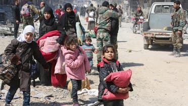 Syrian women and children walk past government soldiers as they evacuate from the town of Jisreen in the southern Eastern Ghouta, on the eastern outskirts of the capital Damascus, on March 17, 2018. (AFP)