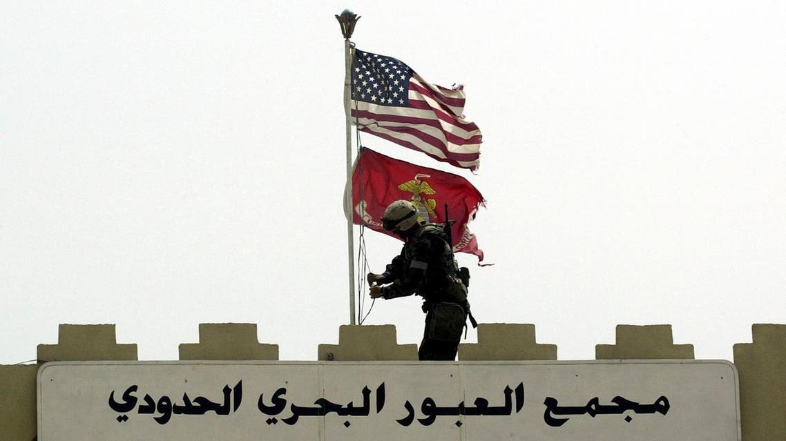 A Marine of the U.S. Marine Expeditionary Unit Fox Company 'Raiders' replaces the Iraqi flag at the entrance to Iraq's main port of Umm Qasr, with the Stars and Stripes and the flag of the Marine Corps, March 21, 2003.(Reuters)