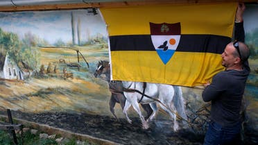 A man fixing the Liberland flag onto a wall in a private compound in Backi Monostor, Serbia, on May 1, 2015. (AP)