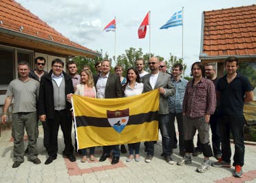 Vit Jedlicka (C) poses with the Liberland flag and future citizenships in the village of Backi Monostor, Serbia, on May 1, 2015. (Reuters)