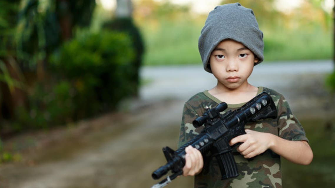 Stock image: asian boy wearing military shirt , with toy gun