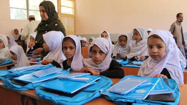 This picture taken on October 8, 2017 shows Afghan school girls looking on as they receive pens and bags from the United Nations Children's Fund (UNICEF) at a school in Lashkar Gah in Helmand province.  NOOR MOHAMMAD / AFP