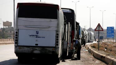 A driver stands next to a bus as he waits to cross into the town of Douma, eastern Ghouta, to evacuate rebels and their families, at Wafideen camp in Damascus, Syria April 1, 2018. REUTERS/Omar Sanadiki