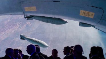 Participants of the Conference on International Security gather together near a big screen showing a Russian warplane unloading its weapons over target in Syria. (AP)