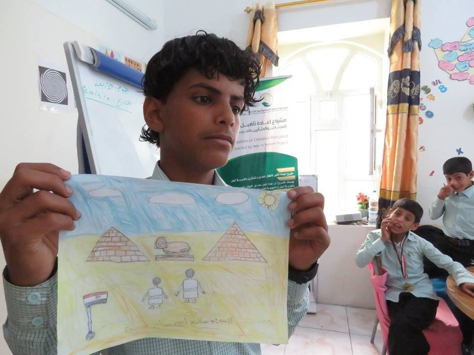 احد الاطفال المجندين يعرض رسمته ضمن انشطة مشروع اعادة التاهيل