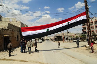 Men raising the Syrian flag in Douma after Syrian government forces entered the last rebel bastion on April 14, 2018. (AFP)