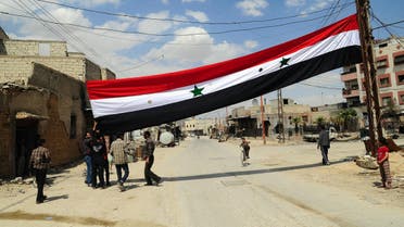 Men raising Syrian flag in Douma after Syrian government forces entered the last rebel bastion on April 14, 2018. (AFP)