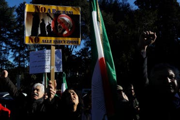 An Iranian opposition group protester holds up a placard bearing a picture of Iran President Hassan Rouhani and writings reading “No to Rouhani no to executions”, during a protest outside the Iran Embassy, in Rome, on Jan. 2, 2018. (AP)