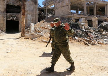Russian forces walk past damaged buildings in Douma during an organized media tour on April 16, 2018. (AFP)