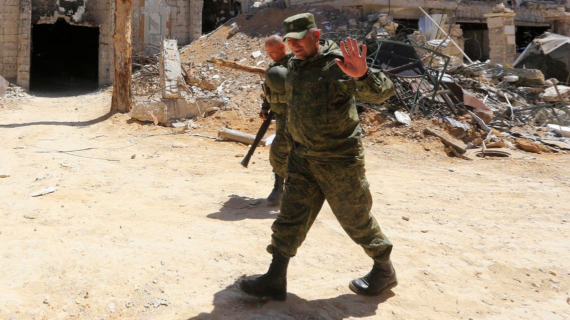 Russian forces walk past damaged buildings in Douma during an organized media tour on April 16, 2018. (AFP)