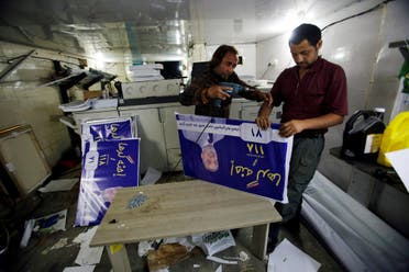 Men work on campaign posters of local candidates ahead of the parliamentary election, in Baghdad on April 14, 2018. (Reuters)