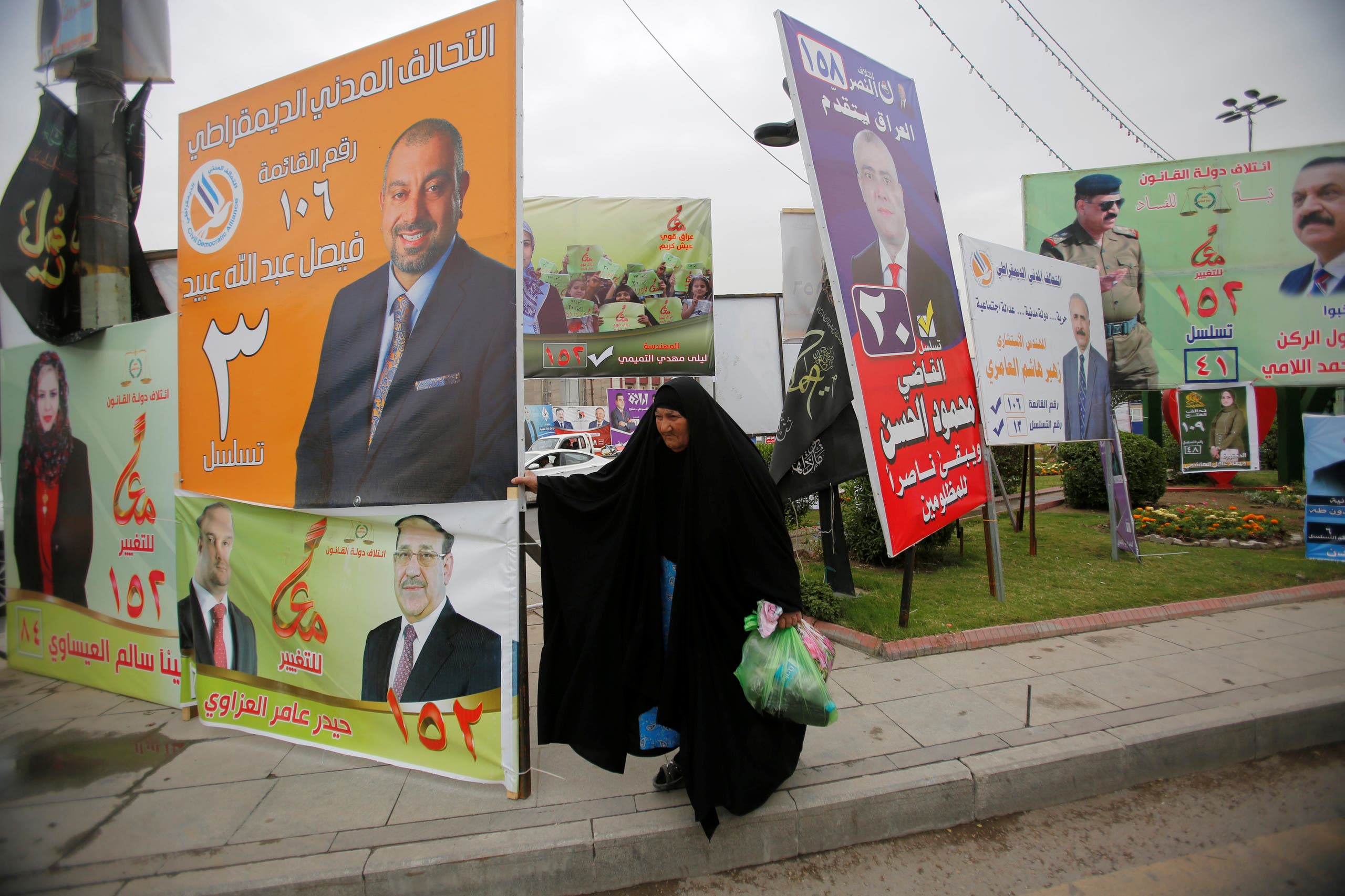 A woman walks past campaign posters of candidates ahead of parliamentary election, in Baghdad, Iraq April 22, 2018. REUTERS/Khalid al Mousily