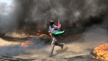 A demonstrator runs during clashes with Israeli troops at a protest where Palestinians demand the right to return to their homeland, at the Israel-Gaza border in the southern Gaza Strip, April 20, 2018. REUTERS/Ibraheem Abu Mustafa