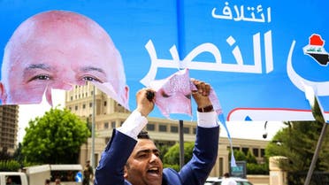 An Iraqi Kurdish man holds up piece he tore from a campaign banner for Iraqi Prime Minister Haider al-Abadi, for the upcoming parliamentary elections in the capital of the northern Iraqi Kurdish autonomous region. (AFP)