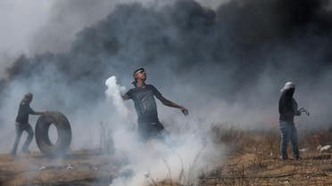 A demonstrator hurls back a tear gas canister fired by Israeli troops during clashes at a protest where Palestinians demand the right to return to their homeland, at the Israel-Gaza border in the southern Gaza Strip, April 27, 2018. REUTERS/Ibraheem Abu Mustafa