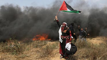 A woman demonstrator holds a Palestinian flag during clashes with Israeli troops at a protest where Palestinians demand the right to return to their homeland, at the Israel-Gaza border in the southern Gaza Strip, April 27, 2018. REUTERS/Ibraheem Abu Mustafa