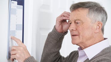 Confused Senior Man With Dementia Looking At Wall Calendar - Stock image... 