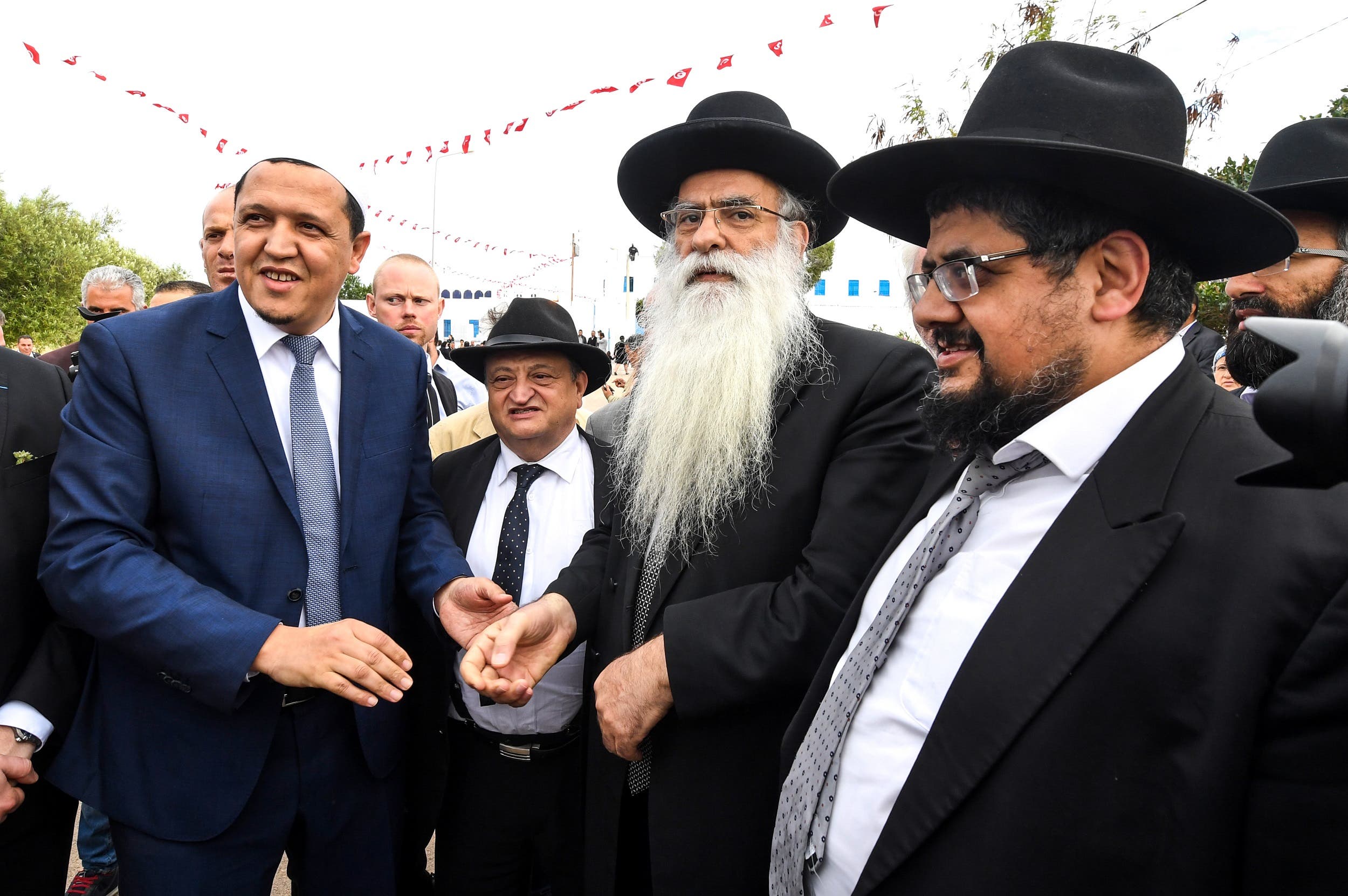 Hassen Chalghoumi (L), the administrative responsible of the municipal Drancy mosque in Seine-Saint-Denis, greets Israeli rabbi Raphael Cohen (C) and his delegation at the Ghriba Synagogue on May 2, 2018. (AFP)
