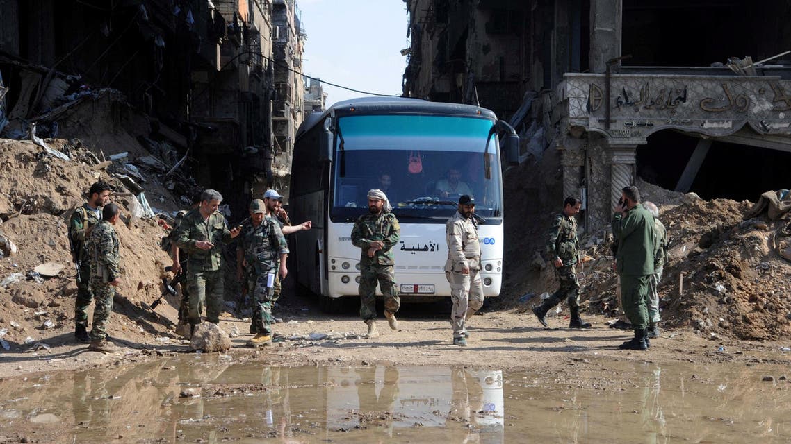 Soldiers loyal to Bashar al Assad seen near a bus carrying rebels from Yarmouk camp in Damascus on April 30, 2018. (Reuters)