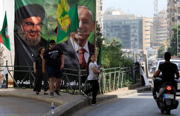 People walk past a campaign banner showing Lebanese Parliament Speaker and candidate for parliamentary election Nabih Berri and Hezbollah leader Sayyed Hassan Nasrallah in Beirut. (Reuters)