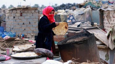 Umm Salem bakes bread in front of her hut at an encampment for the displaced outside Baghdad, Iraq. (AP)