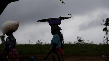 Storm clouds loom as a woman carries maize and an umbrella on her head near Malawi's capital Lilongwe. (Reuters)