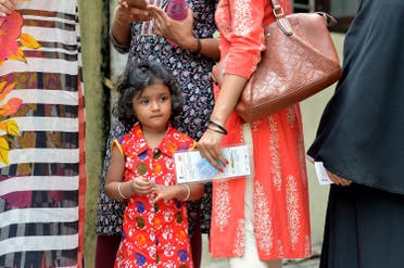 An Indian child looks on as voters queue to cast their ballots in the Karnataka Legislative Assembly Elections at a polling station in Bangalore. (AFP)