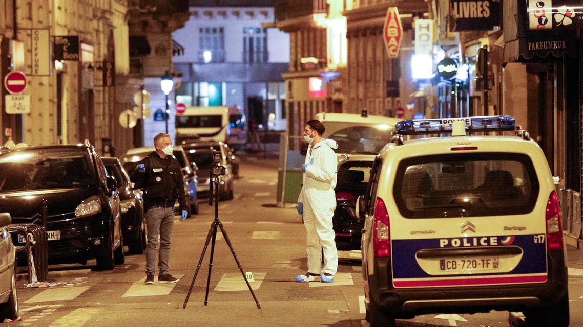 A forensic officer (R) and a French policeman (L) stand next to a numbered reference index pad and a camera on a tripod on Saint Augustin street in Paris after one person was killed and several injured by a man armed with a knife,